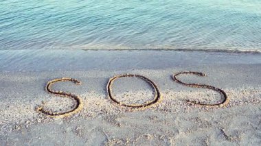 Kuma yazılan SOS yazısı. Sahilde çekim yapmak..