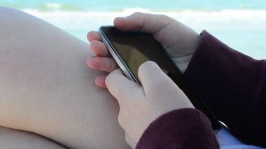 Denize karşı akıllı telefonu olan kız, plaj. Sahilde çekim yapmak..