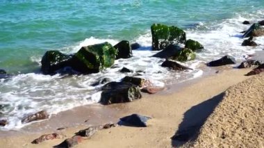 Deniz dalgaları taşlara çarpıyor. Deniz kıyısında ateş ediyorlar. Yavaş çekim.