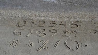 Kumsala yazılmış rakamlar ve işaretler. Sahilde çekim yapmak..