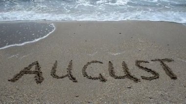 Kumsaldaki ayın isminin yazılı olduğu bir yazı. Sahilde çekim yapmak..