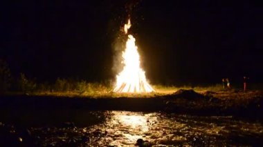 Nehrin arkasında yangın var. Ivan Kupala 'nın tatili için yangın, Temmuz, yaz, Ukrayna.