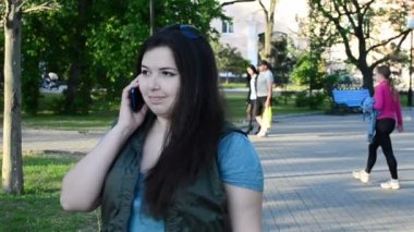 Kız hareket sırasında telefonla konuşur. Şehirde ateş ediliyor.