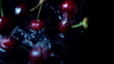 Siyah arka planda tatlı kirazın suya düşüşü. Yavaş çekim.