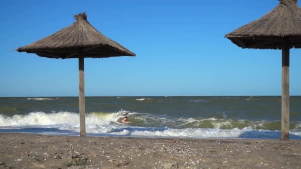男は海の波に泳いでいる スローモーション — ストック動画