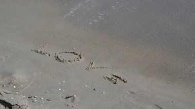 Aşk sözcükleri. Aşk kelimesi, bir dalga tarafından silinip gider.