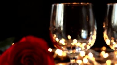 Şarap kadehleri ve gül arkaplanda parlak çelenkler.