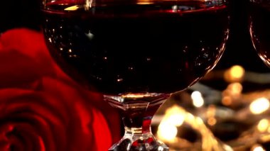 Şarap kadehleri ve gül arkaplanda parlak çelenkler.