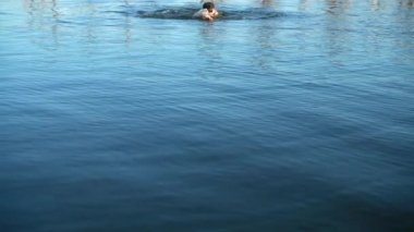 Adam yaz akşamında denizde yüzer. Yavaş çekim.