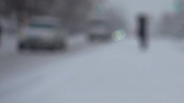Şehirde kar fırtınası. Karla kaplı yolda bir araba hareket ediyor. Odaklanamıyorum. Kışın çekim..