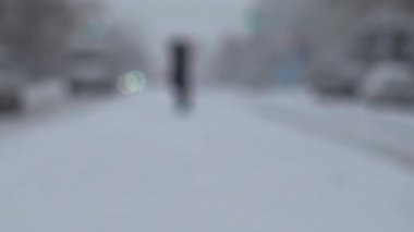 Şehirde kar fırtınası. Karla kaplı yolda bir araba hareket ediyor. Odaklanamıyorum. Kışın çekim..