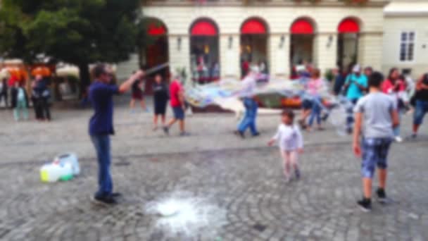 Homem Entretém Crianças Com Bolhas Sabão Praça Cidade Fora Foco — Vídeo de Stock