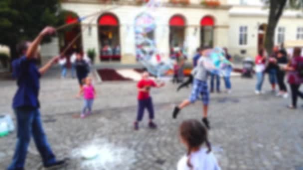 Чоловік Розважає Дітей Мильними Бульбашками Міській Площі Межами Фокусу — стокове відео