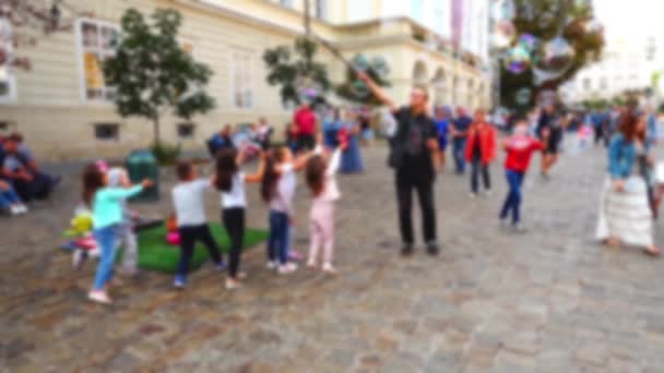 Man Vermaakt Kinderen Met Zeepbellen Het Stadsplein Onscherp — Stockvideo