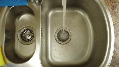 Bir kadın bulaşık yıkıyor bir su deresinin altında.