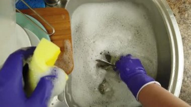 Bir kadın bulaşık yıkıyor bir su deresinin altında.