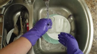 Bir kadın bulaşık yıkıyor bir su deresinin altında.