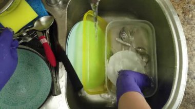 Bir kadın bulaşık yıkıyor bir su deresinin altında.