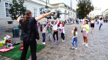 LVIV, UKRAINE - 3 AĞUSTOS 2019: Bilinmeyen adam, çocuklar için sabun köpüklerinin şehrin meydanlarına çıkmasına izin veriyor. Yavaş çekim.