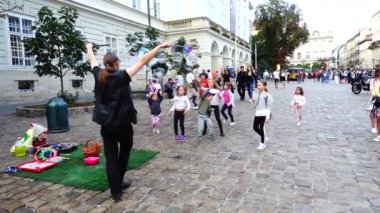 LVIV, UKRAINE - 3 AĞUSTOS 2019: Bilinmeyen adam, çocuklar için sabun köpüklerinin şehrin meydanlarına çıkmasına izin veriyor. Yavaş çekim.
