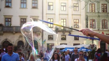LVIV, UKRAINE - 25 Ağustos 2019: Bilinmeyen bir adam şehir meydanında sabun köpüklü çocukları eğlendiriyor. Yavaş çekim.