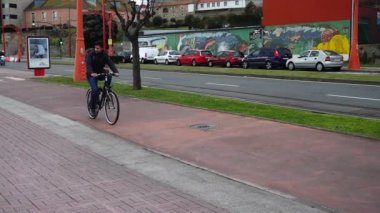 LA CORUNA, İspanya - 2 Nisan 2018: Bilinmeyen insanlar şehrin deniz setinde bisiklet sürmekle meşgul. Yavaş çekim.