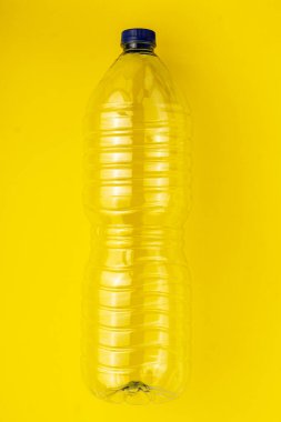 Sarı arka planda boş plastik su şişesi. Sarı konteynıra çöp toplama kavramı
