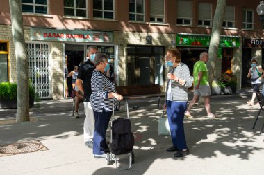 BARCELONA; İspanya - 25 Mayıs 2020: Barcelona 'da Coronavirus hastalığının (COVID-19) birinci safhasının ilk günü, maskeli yaşlı insanlar izin verilen saatlerde sokakta konuşuyorlar