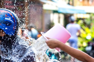 Patong, Phuket, Tayland - 13.04.2014. Songkran Festivali Asyalı kız yanından geçen insanlarla bisikleti sırılsıklam ediyor