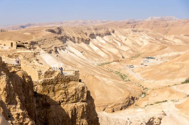 Turistler, İsrail 'in Masada kalesini ele geçirmek için Romalıların tepesine bakıyor.