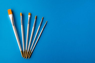 Flay lay lay, üst görünüm masa. Mavi arkaplanda farklı sanatçı fırçaları