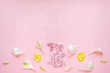Tepeden paskalya komik tavşanı. Çiçek yapraklı dekoratif yumurtalar. Pembe arka planda dümdüz yatıyordu. Boşluğu kopyala
