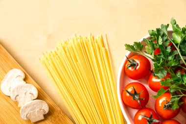 Çiğ spagetti, domates, mantar, kesim tahtası, ahşap arka planda maydanoz, üst görünüm kopya alanı