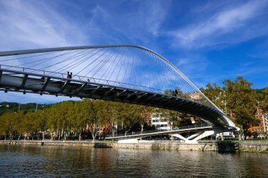 Bilbao, Bizkaia, İspanya - 4 Ekim 2017. Zubizuri Köprüsü, Santiago Calatrava, Bilbao, İspanya. İnsanlar Nervion Nehri üzerindeki asma bir yaya köprüsünde yürüyor.