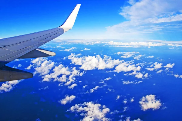 Mavi gökyüzünde bir uçağın kanadı Bir uçak penceresinden kümülüs bulutları