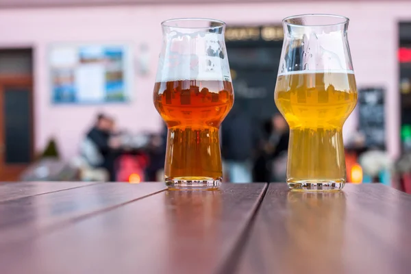 two glasses of beer on table edge