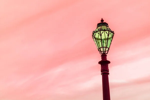 Poste lâmpada verde no fundo céu vermelho — Fotografia de Stock