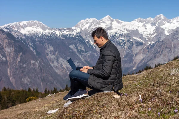 Młody człowiek freelancer za pomocą laptopa w górach — Zdjęcie stockowe