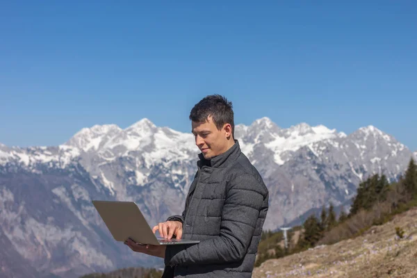 Joven freelancer utilizando portátil en las montañas — Foto de Stock
