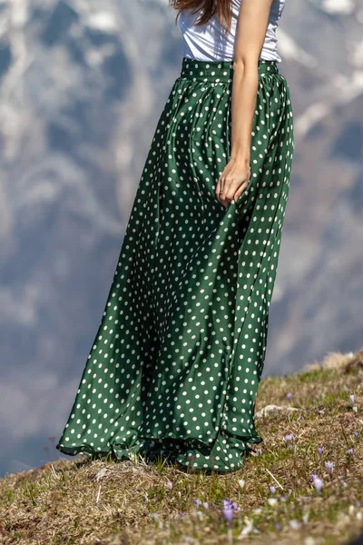 young woman in green dotted skirt in mountains