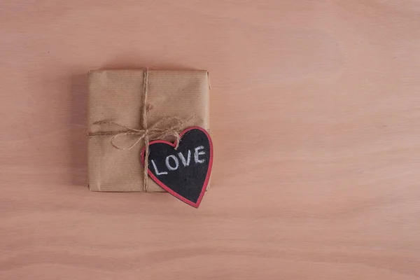 Ett papper inslagen gåva med trä hjärta plywood — Stockfoto