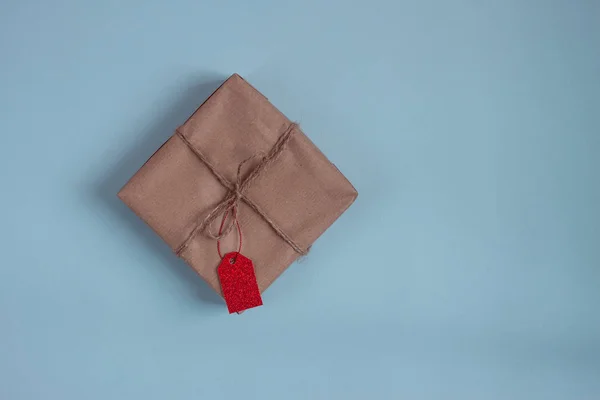 Paper wrapped gift with red tag on blue background — Stock Photo, Image