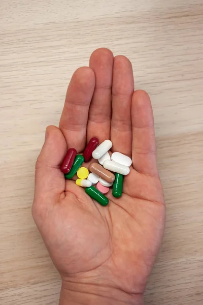 Рука с таблетками разных цветов — стоковое фото