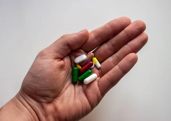 Рука с таблетками разных цветов — стоковое фото