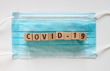 Tahta küplü cerrahi maske ve kelime covid-19