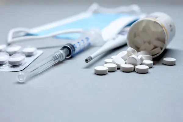 Медицинская маска и таблетки на столе рядом с бутылками — стоковое фото