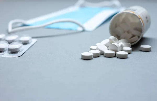 Masque médical et pilules sur la table à côté des bouteilles — Photo