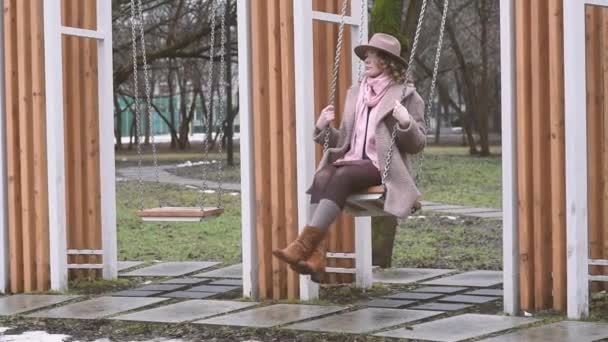 Jeune Femme Solitaire Dans Chapeau Écharpe Rose Sur Les Balançoires — Video