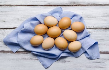 Hassas mavi peçetedeki tavukların yumurtaları ahşap arka planda.