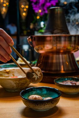 Bir insanın yemek çubuklarını tutarken ve Asyalı gurmeler yerken çekilmiş bir fotoğrafı. 
